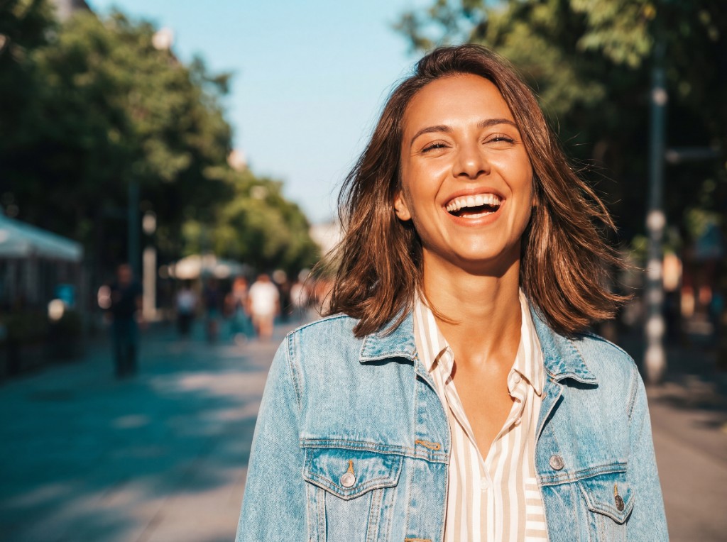 Lachende Frau draußen als Symbol für finanzielle Freiheit
